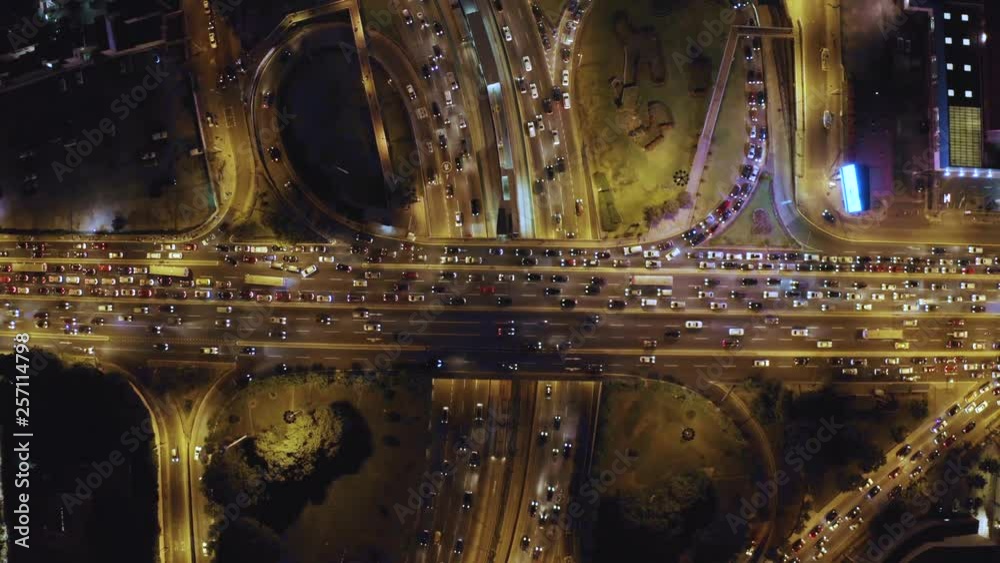 Aerial top view of cloverleaf  Interchange road at rush hour. Birds eye of city traffic at night time. City lights and cars stuck in Javier Prado and Via Expresa highways.