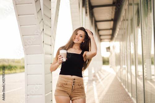 Beautiful young woman drink coffee and walking near the mall.