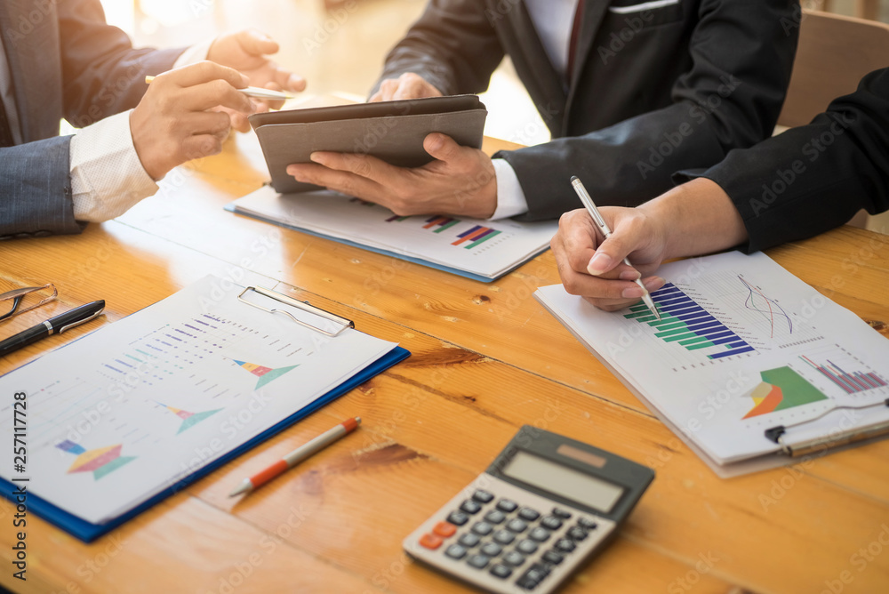 Group of business people working with laptop and tablat and paper graph in the office room. Accounting concept. Group of business people working with laptop and tablat and paper graph in the office room. Accounting concept.