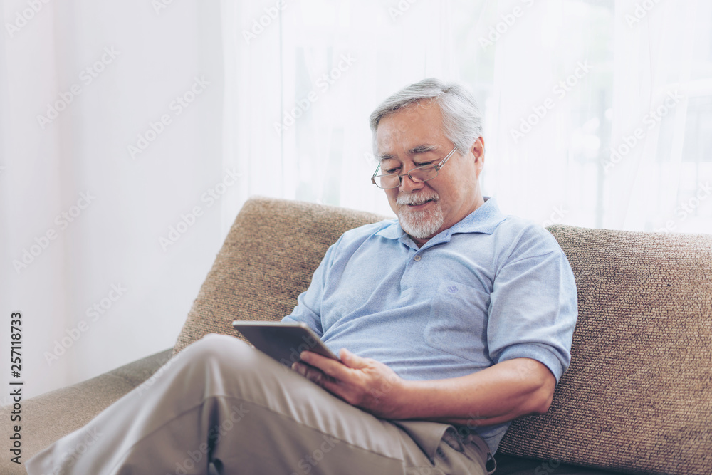 Senior Male using a smartphone , smiling feel happy on sofa at home - lifestyle senior elderly people concept Senior Male using a smartphone , smiling feel happy on sofa at home - lifestyle senior elderly people concept