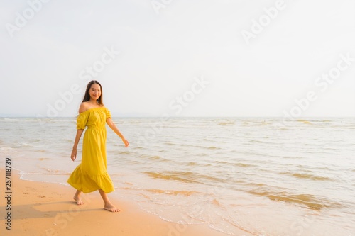 Portrait beautiful young asian woman walk on the beach and sea ocean with smile happy relax