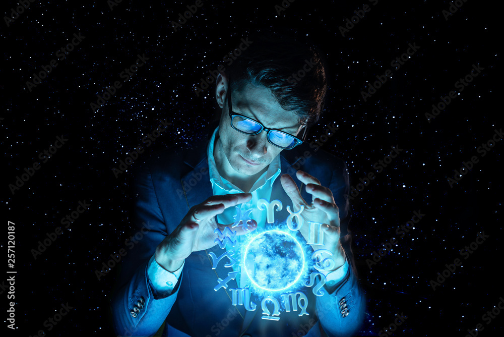 Fototapeta premium Businessman holding hands over the magic sphere with a horoscope to predict the future. Astrology as a business