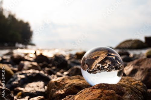 Crystal glass balls are displayed on a rocky coast with turquoise clouds covered with a summer background. Can be used for displaying or editing your background products Business travel © Waraphot