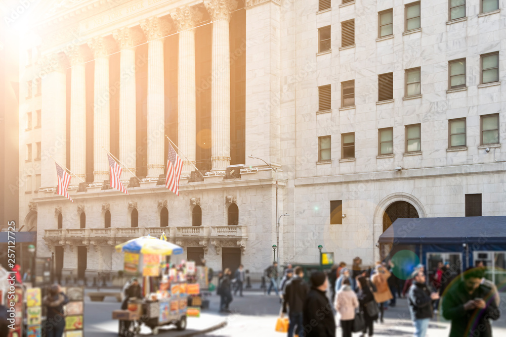 Sunlight shines on the crowds of people and historic buildings along Wall Street in the financial district of lower Manhattan, New York City