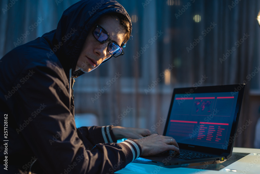 Man in the hood looking in the camera. Hacker attacks and stealing access databases with passwords. Cyber security Man in the hood looking in the camera. Hacker attacks and stealing access databases with passwords. Cyber security