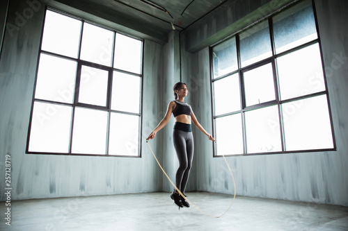portrait of asian sport young woman jumping rope in the gym