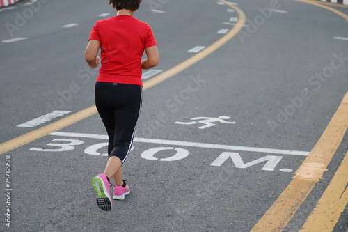 Closeup of young Asian woman jogging in the track on the road of public park in the evening. Good health promotion  and smart activity in self-reliance basis.