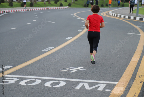 Closeup of young Asian woman jogging in the track on the road of public park in the evening. Smart and healthy activity of people in modern world. 
