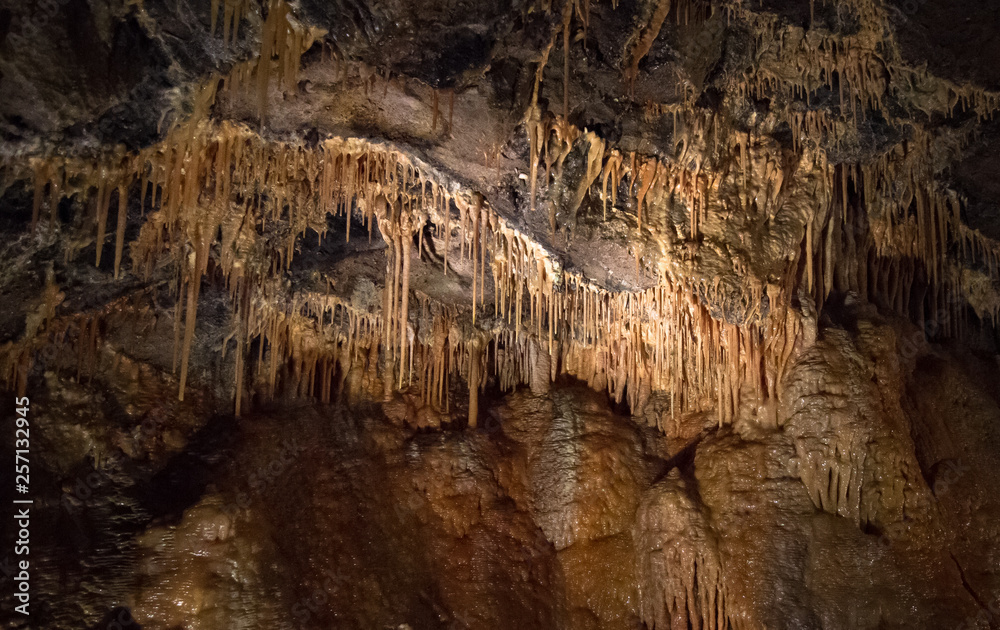 Stalactites line the wall and ceiling of a cave in the Peak District, England. Stalactites line the wall and ceiling of a cave in the Peak District, England.