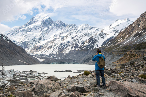 Tourist standing and looking to the beautiful view of Hooker glacier lake and Mount Cook (3,764 metres) the highest mountains in South Island of New Zealand.