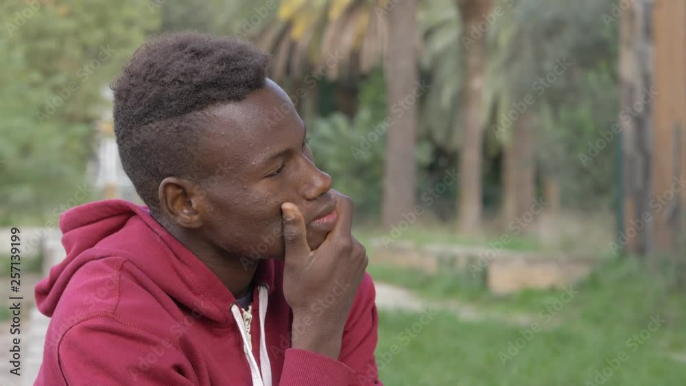 Thoughtful daydreaming young black african guy alone in the park Thoughtful daydreaming young black african guy alone in the park