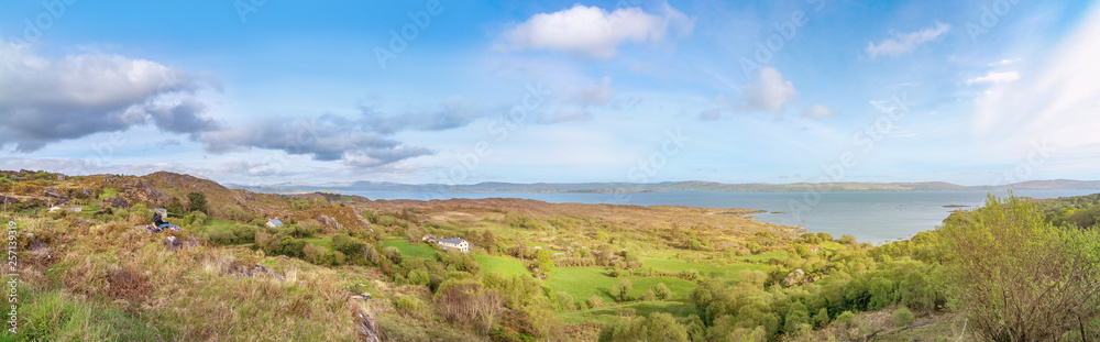 Two tourists sitting and looking at the panoramic landscape in Beara Peninsula Two tourists sitting and looking at the panoramic landscape in Beara Peninsula
