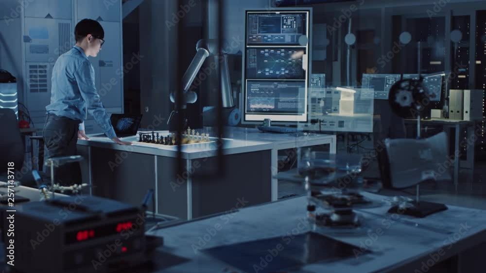 Professional Japanese Development Engineer is Testing an Artificial Intelligence Interface by Playing Chess with a Futuristic Robotic Arm. They are in a High Tech Modern Research Laboratory. Professional Japanese Development Engineer is Testing an Artificial Intelligence Interface by Playing Chess with a Futuristic Robotic Arm. They are in a High Tech Modern Research Laboratory.