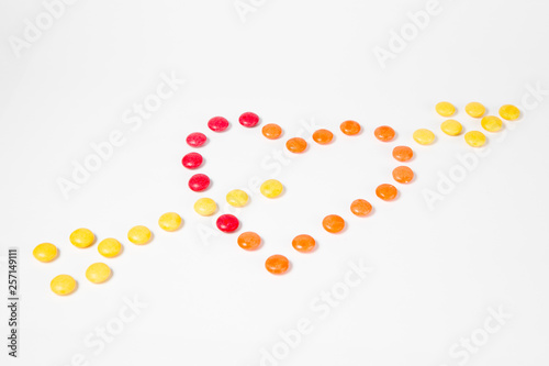 Shape of heart pierced with arrow - I love you - made from colorful sweet candies.