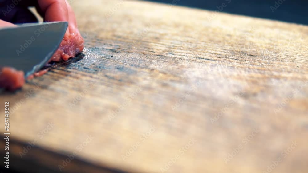 Cutting Meat Into Small Pieces On Wooden Table.Slicing Small Raw Piece Of Meat.Cook Cuts Beef Meeat In Small Pieces.Slicing Meat Into Small Pieces On Cutting Board, Close Up.Man Slicing Raw Meat.