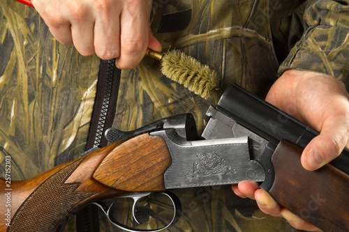 hunter cleans the barrels of his shotgun with a ramrod