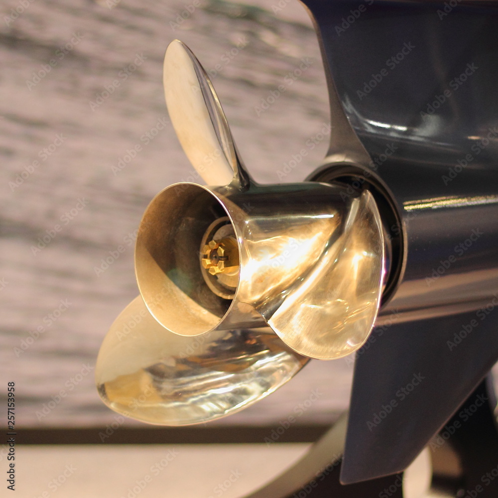 Foto Stock Close up golden stainless steel motor boat propeller on gear  drive shaft of outboard motor - rear side view in blue color | Adobe Stock