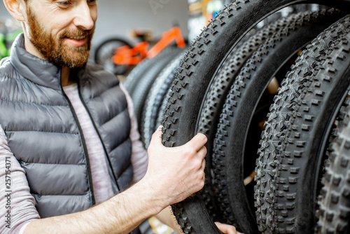 Man taking new bicycle tire from the shelves, buying bicycle parts at the sports shop