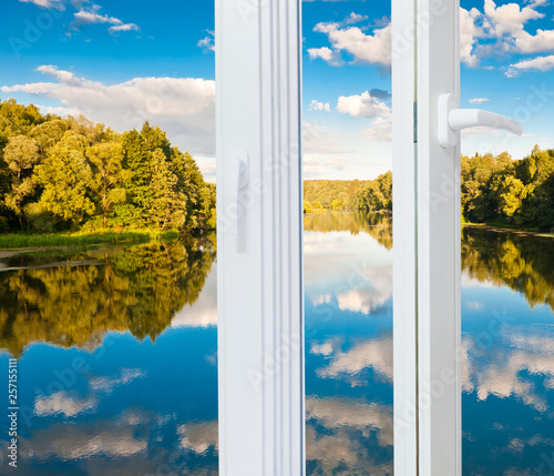 Window and landscape with forest, river and white clouds on the blue sky