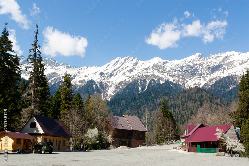Snow on the mountains. Spring landscape on the background of houses