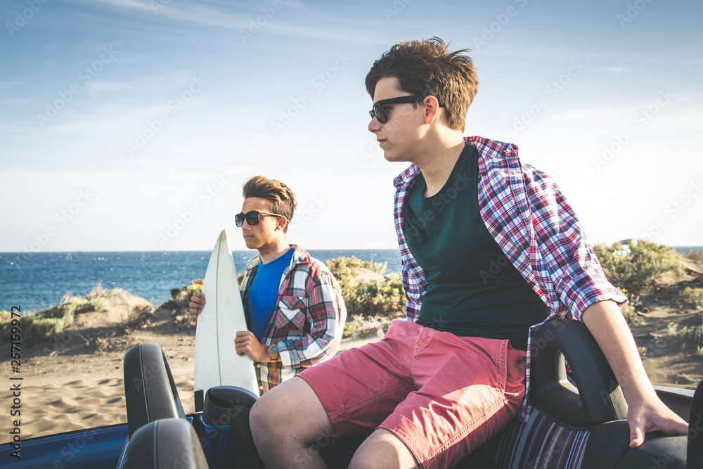 Two young happy teenager best friends looking the horizon with surf board Profile portrait of two happy young boys outside. Concept of friendship. Relax after beautiful exotic day on the ocean waves