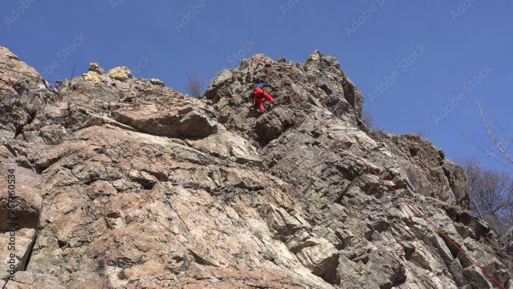 Climbing on the rocks. Climbing equipment, large rock and climbing man. Extreme sports with risk. Gray stones, confident people rise to the goal. Active rest in the mountains. Rocky terrain. Climbing on the rocks. Climbing equipment, large rock and climbing man. Extreme sports with risk. Gray stones, confident people rise to the goal. Active rest in the mountains. Rocky terrain.