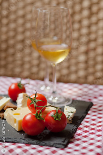 Romantic dinner for a couple on Saint Valentine's day: two glasses of cold white wine and gourmet french cheese plate with bread and fresh tomatoes. Nicely served on a red and white napkin