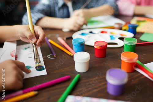 Fototapeta Naklejka Na Ścianę i Meble -  Closeup of children painting pictures, focus on art supplies paints, pencils and crayons, copy space