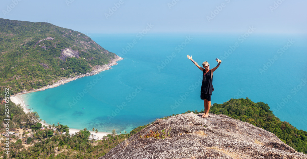 Beautiful stylish young girl woman on top of a mountain overlooking the sea, human and nature, vacations and travel