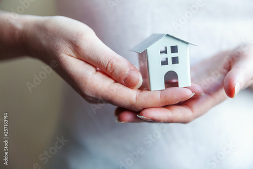 Female woman hands holding small miniature white toy house. Mortgage property insurance dream moving home and real estate concept