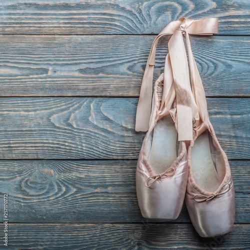 Pointe shoes ballet dance shoes with a bow of ribbons hang on a nail on a wooden background. photo