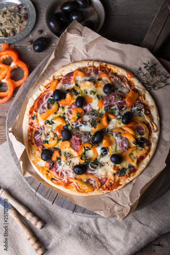 Pizza with tomatoes, mozzarella cheese, black olives and basil. Delicious italian pizza on wooden pizza board.