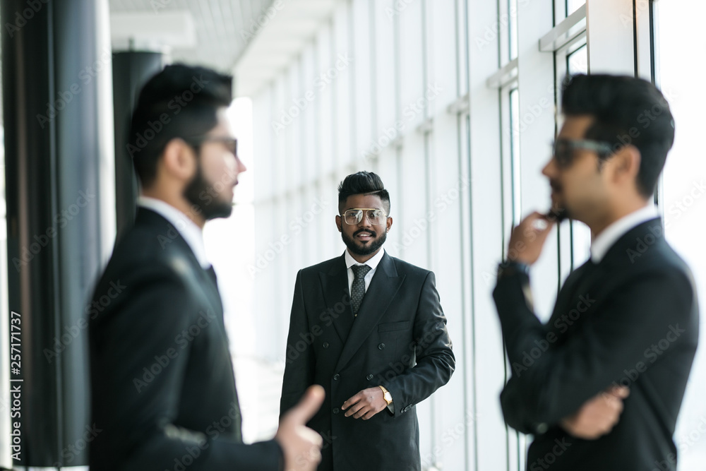 Three asian corporate executives standing in front of collegue discussing plans in modern office Three asian corporate executives standing in front of collegue discussing plans in modern office