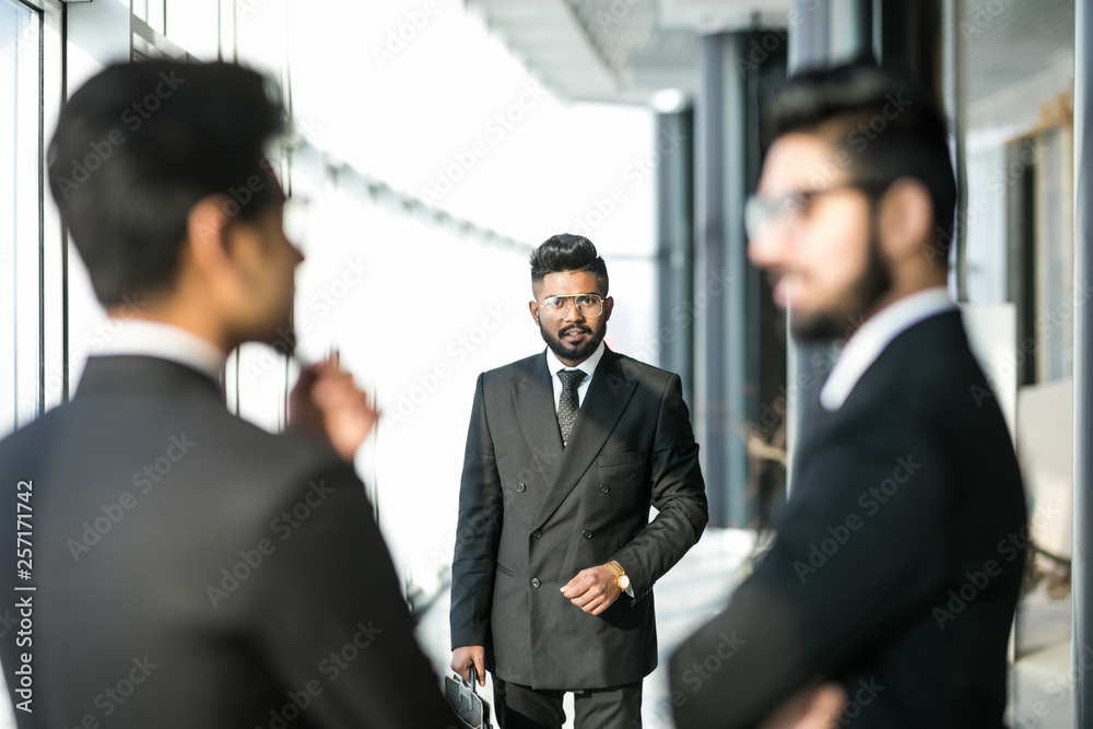 Three asian corporate executives standing in front of collegue discussing plans in modern office Three asian corporate executives standing in front of collegue discussing plans in modern office