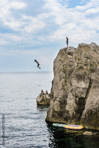 Man jumps from a cliff into the sea.