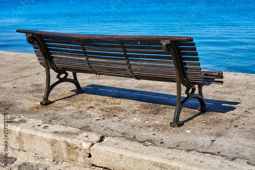 Single old-fashioned cast iron and wood park bench on a sunny day © timltv