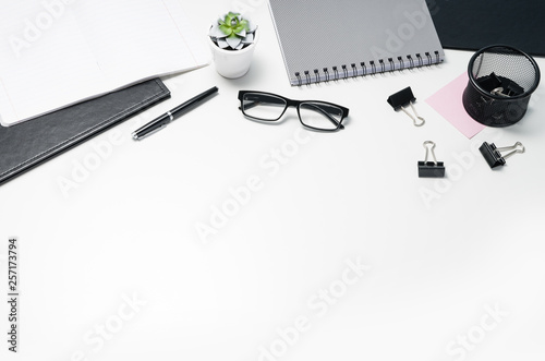 White office desk table with blank notebook, computer, supplies and coffee cup. Top view with copy space. Flat lay.