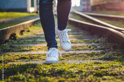 Woman wearing white sneakers running on railroad track