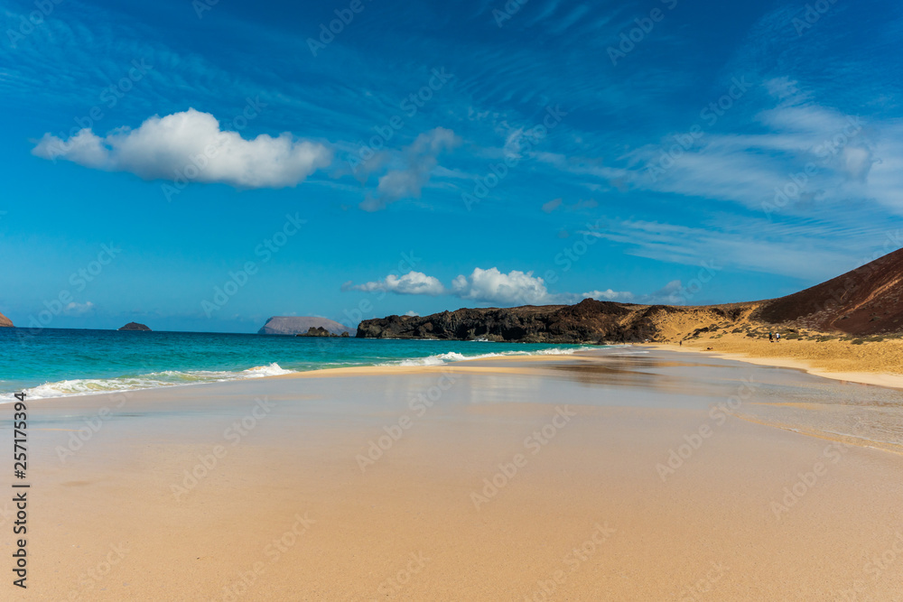 Untouched white sand beach with crystal clear waters on a beautiful summer day. Exotic landscape of Playa de las Conchas one of the most popular beaches on La Graciosa Island, Canary, Spain.