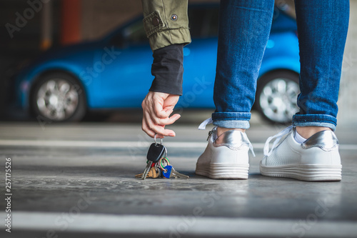 Woman found lost car key at parking lot. Blurry blue car in background © encierro