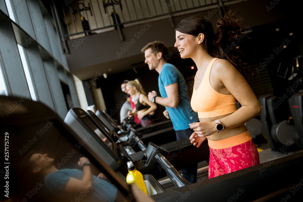 young people running on treadmills in modern gym young people running on treadmills in modern gym