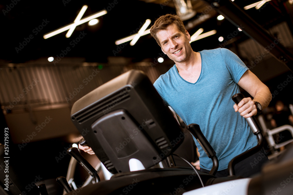 Man doing exercise on elliptical cross trainer in sport fitness gym club Man doing exercise on elliptical cross trainer in sport fitness gym club