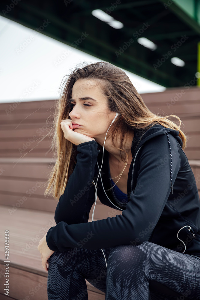 Sad and frustrated sporty young woman sitting outdoor