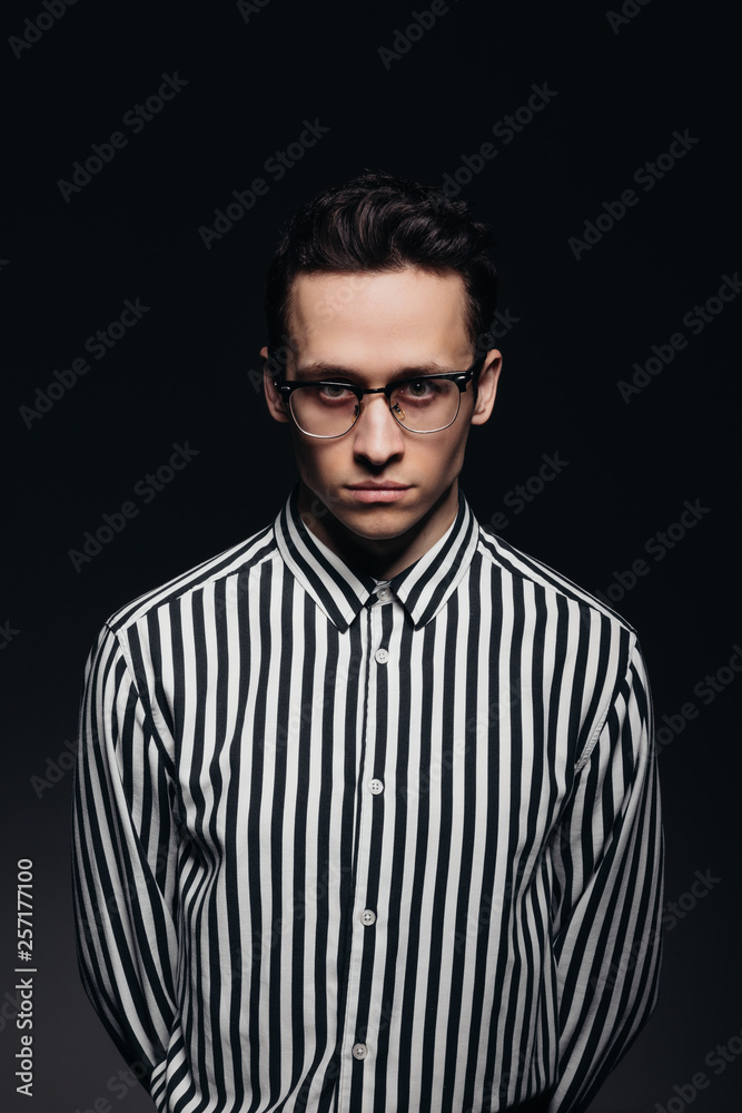 Obraz premium Handsome man with glasses, toung man in striped shirt, black background