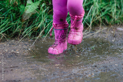 A child runs in rubber boots through muddy puddles. The concept of freedom and child development