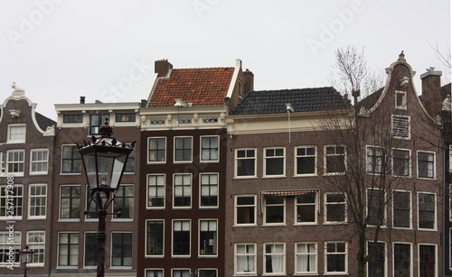 tall Dutch buildings built in red bricks in the style of Amsterdam. cold autumn day, gray and cloudy