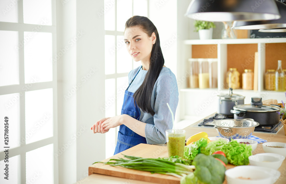 Portrait of young woman standing with arms crossed against kitchen background Portrait of young woman standing with arms crossed against kitchen background