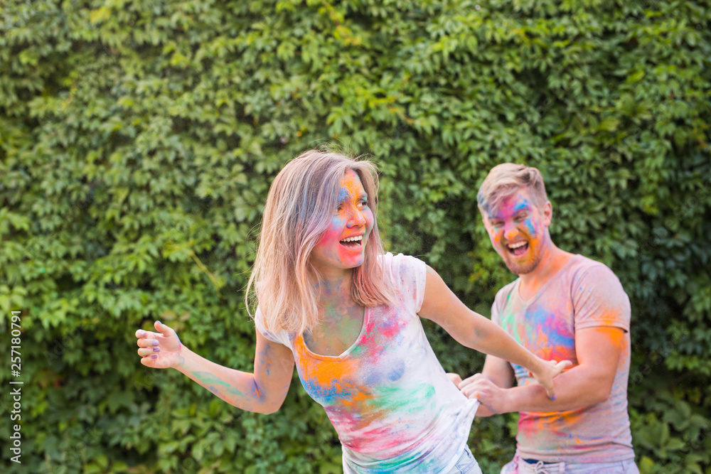 Fototapeta premium Friendship, festival of holi, people concept - young couple playing with colors at the festival of holi