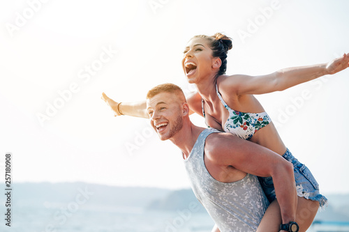 Woman with arms outstretched enjoying piggyback ride,Woman with arms outstretched enjoying piggyback ride