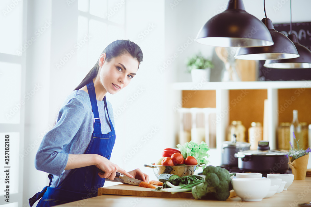 Young woman cutting vegetables in kitchen at home